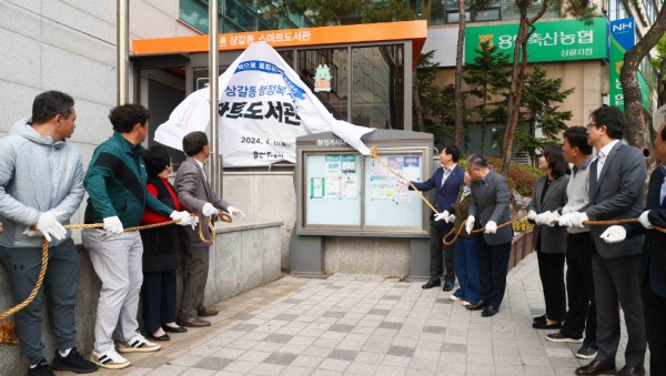 3-3. 지난 11일 기흥구 상갈동 행정복지센터 1층 야외 부스에서 열린 스마트도서관 11호점 개관식에서 이상일 용인특례시장(오른쪽에서 일곱번째) 등 참석자들이 제막식을 하고 있다..jpg