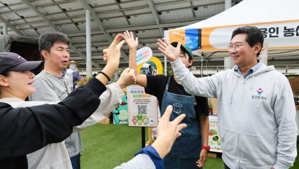 7. 이상일 용인특례시장이 18일 시청 광장에서 열린 책 속 한 줄 쓰Go, 농산물 받Go 행사에서 시민들과 인사를 나누고 있다..jpg